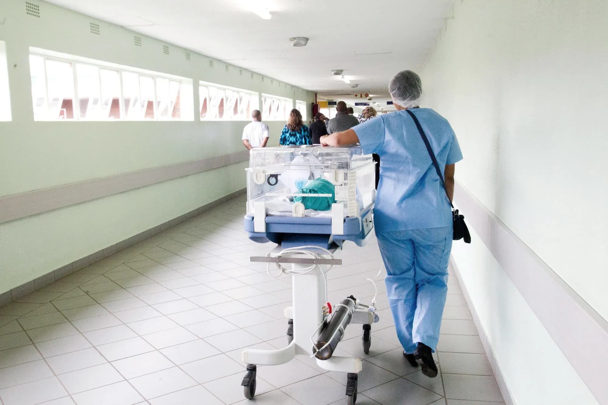 Pflegekraft schiebt ein Bett durch einen hellen Klinikflur